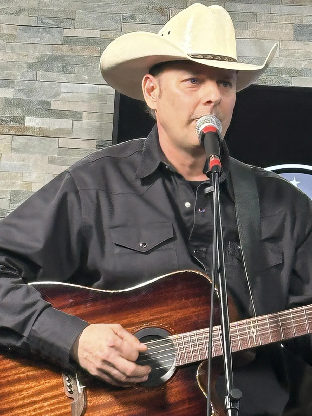 Country artist Fred Winston singing and playing acoustic guitar in his cowboy hat